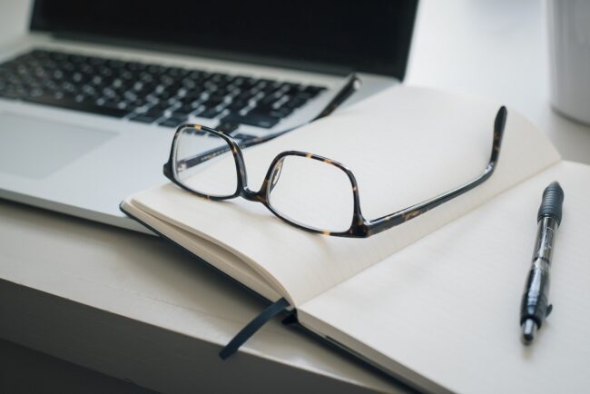 Imagen de estudio de fuentes secundarias. Escritorio con ordenador, gafas cuaderno y bolígrafo
